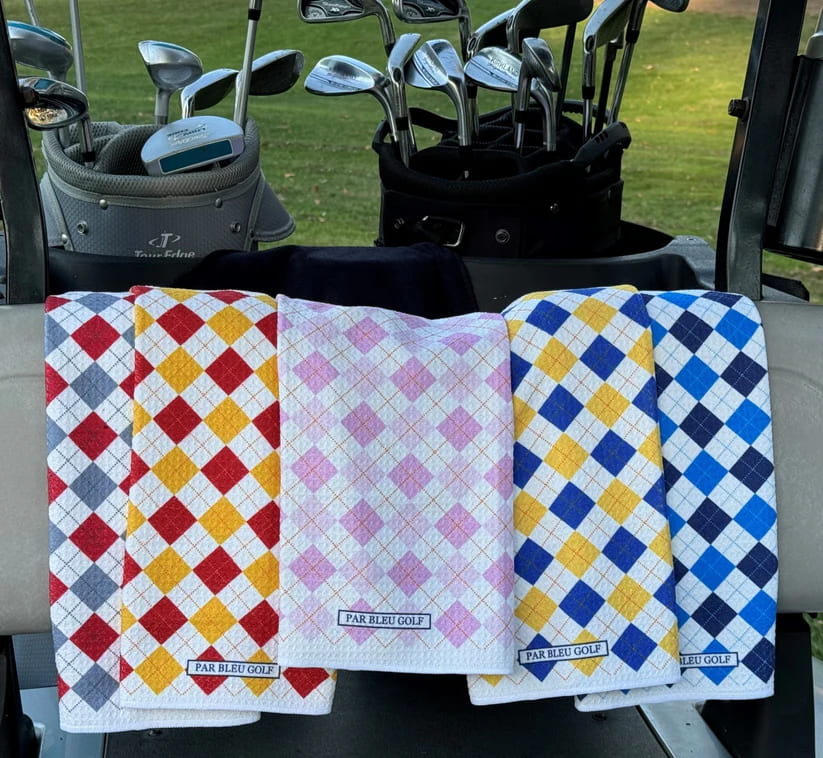 Red, pink, and blue argyle golf towels from Par Bleu displayed together on golf cart bench