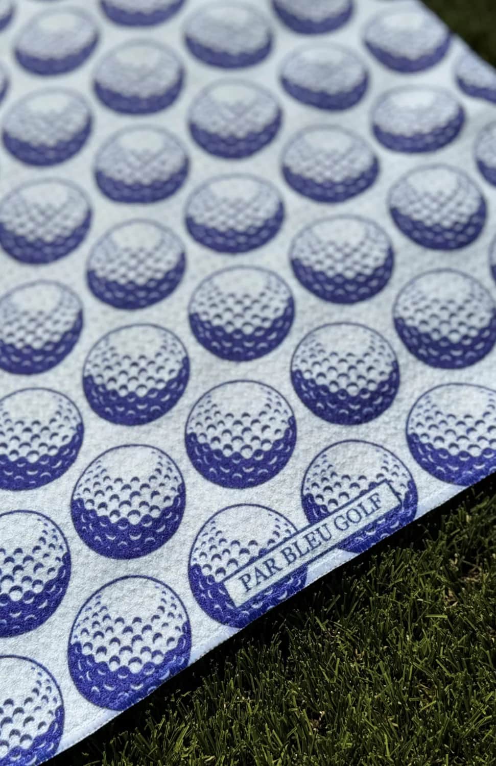 Detailed macro shot of the towel’s blue and white golf ball pattern and textured waffle weave—showcasing softness and durability.