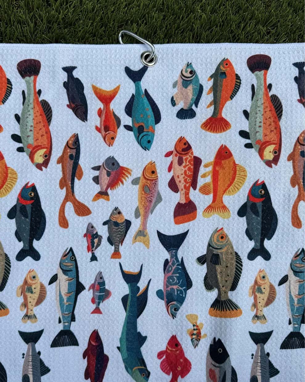Fish-print microfiber golf towel hanging by durable carabiner clip, perfect for golf bags
