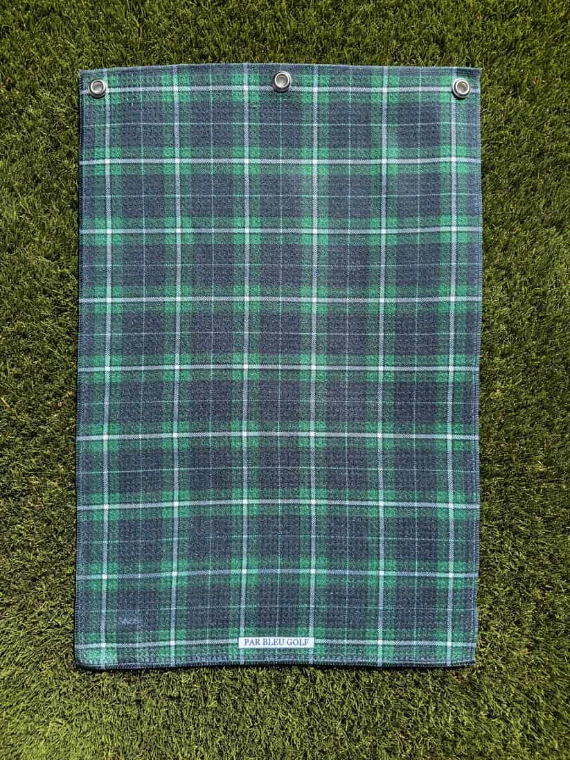 Microfiber plaid towel laid flat on turf, featuring dark green and navy blue tartan pattern