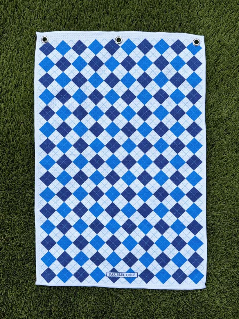 Blue & navy plaid golf towel laid flat on grass, made with soft and durable microfiber