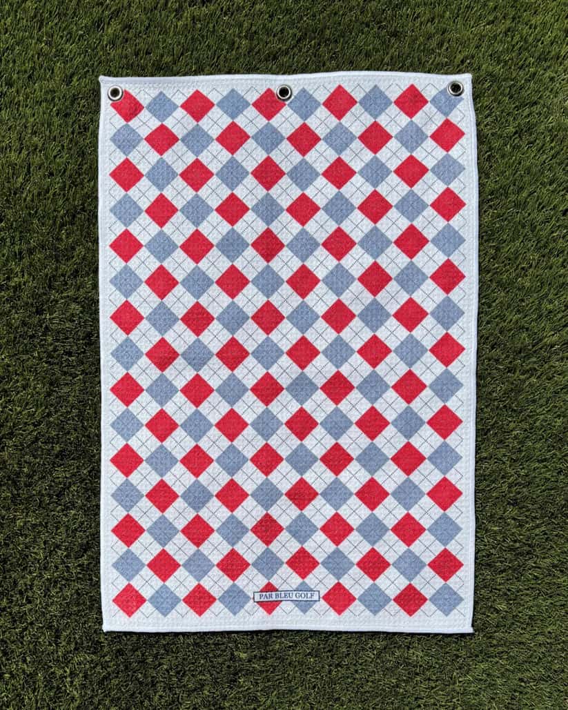 Red and grey plaid golf towel laid flat on grass, featuring soft microfiber and stylish diamond design