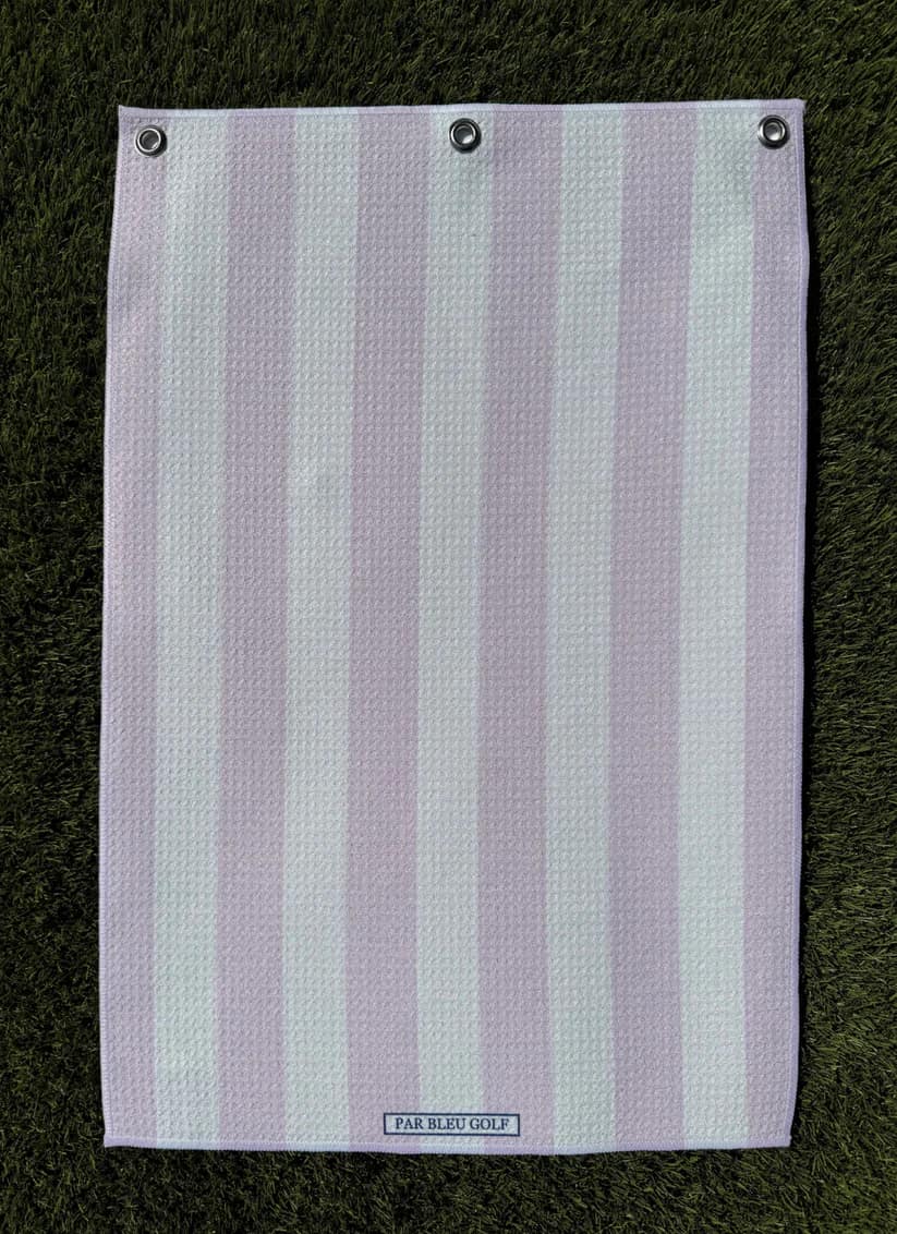 Soft pink and white striped microfiber towel laid flat on green grass, lightweight golf towel for her
