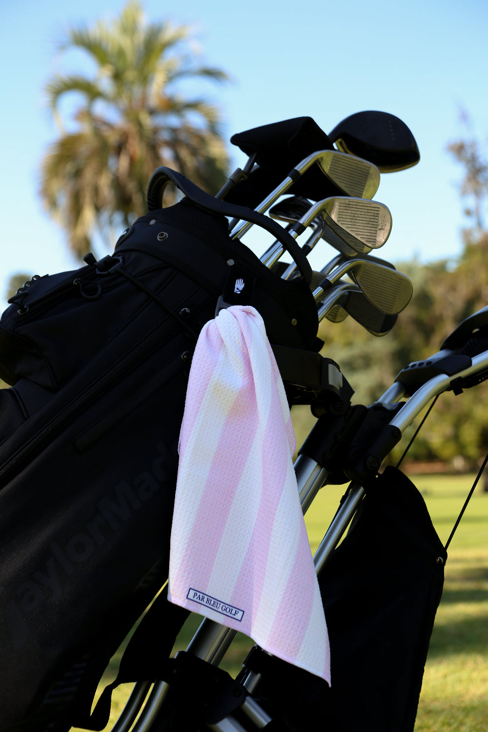 Light pink and white striped golf towel clipped to golf bag, great gift for stylish women golfers