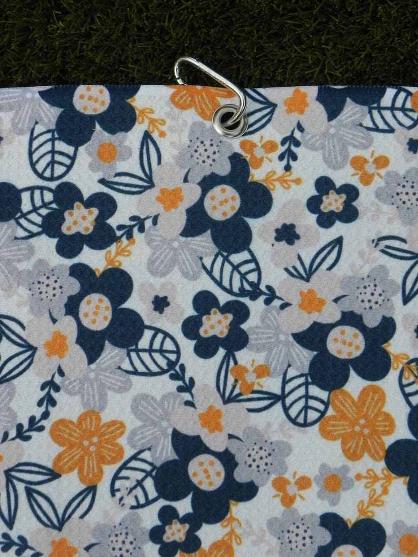 Floral golf towel for women in shades of grey and yellow, hanging vertically with secure metal carabiner
