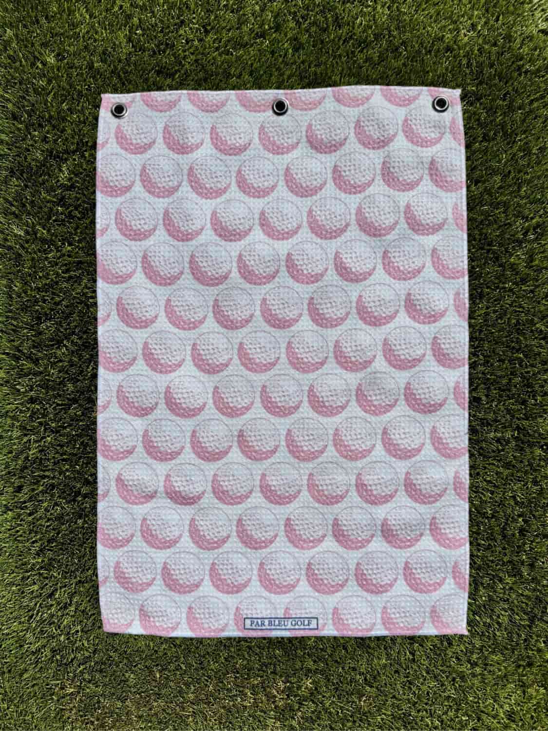 The Golf Ball: Pink towel laid flat on grass, showing full pattern design