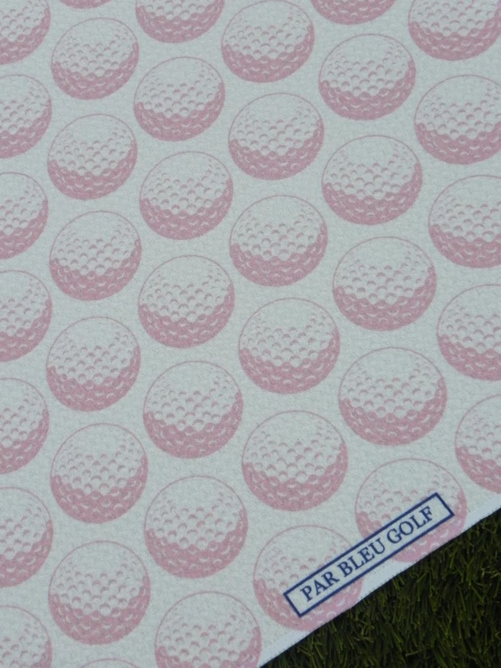 Close-up of pink golf ball pattern with Par Bleu logo tag on towel