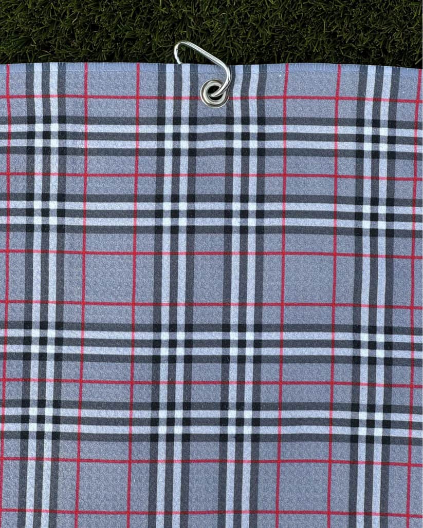 Grey plaid golf towel hanging vertically with metal carabiner, featuring red and black stripe