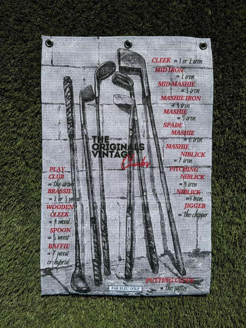 Retro-inspired golf towel laid flat, showing The Originals club illustration in black and red on light background