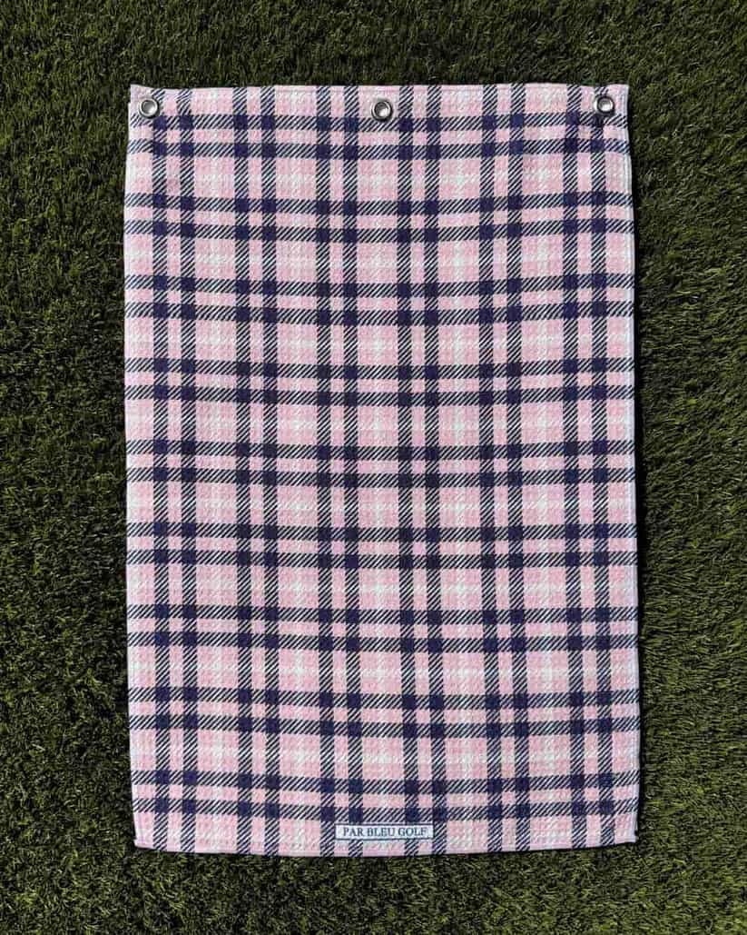 Overview of pink plaid golf towel laid on the grass