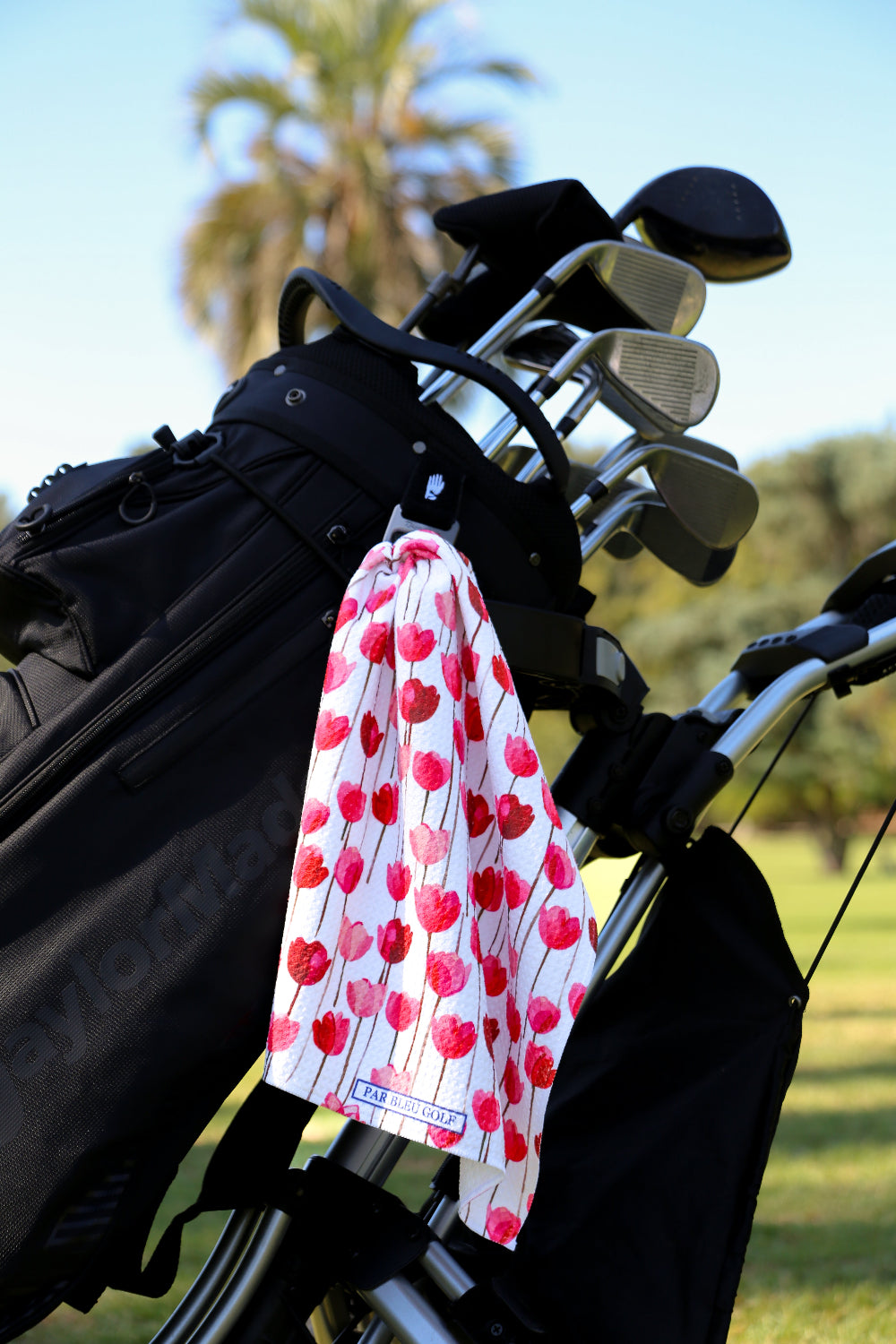 Feminine floral golf towel clipped to black golf bag on course, perfect gift for women who golf