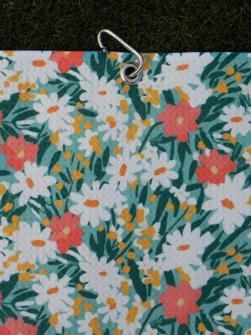 Stylish women’s golf towel with colorful floral design, hanging with silver carabiner for easy golf bag attachment