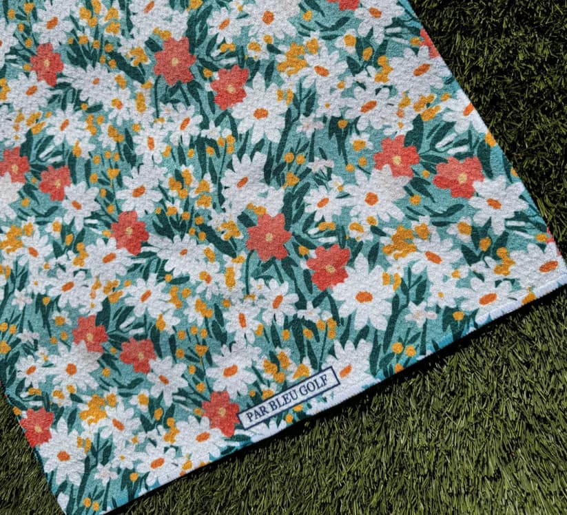 Close-up of The Teal & Orange Floral women’s microfiber golf towel featuring vibrant daisy pattern and Par Bleu logo