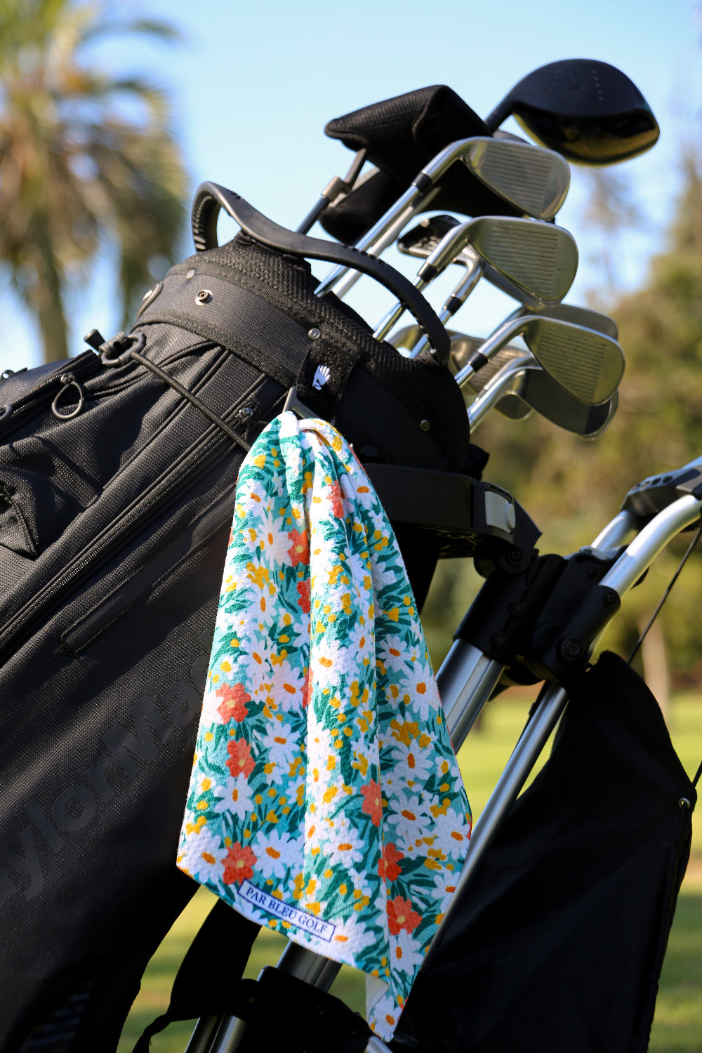 Bold and feminine floral golf towel clipped to golf bag, perfect accessory for women golfers