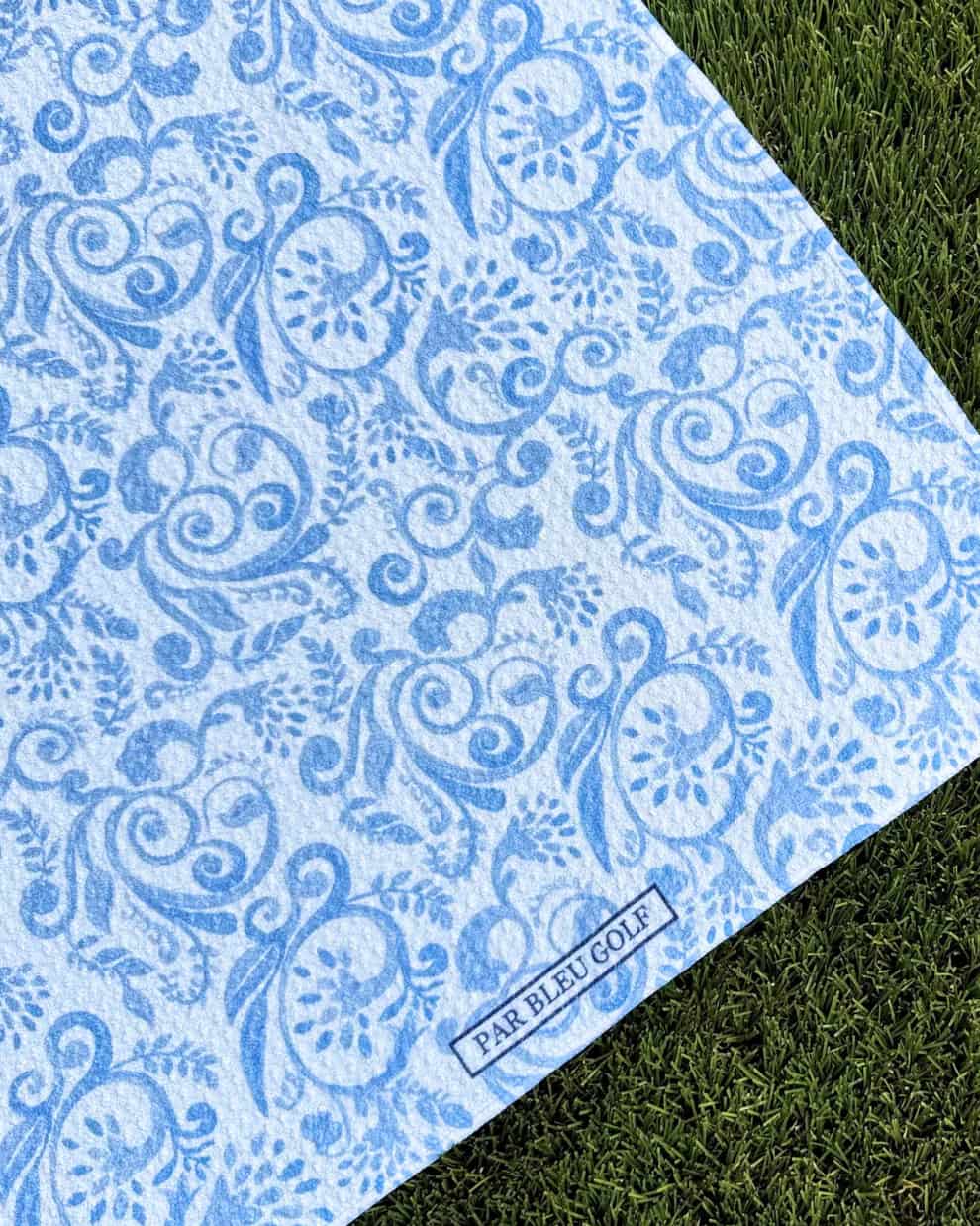 Close-up of blue toile golf towel with intricate vintage pattern and Par Bleu logo tag