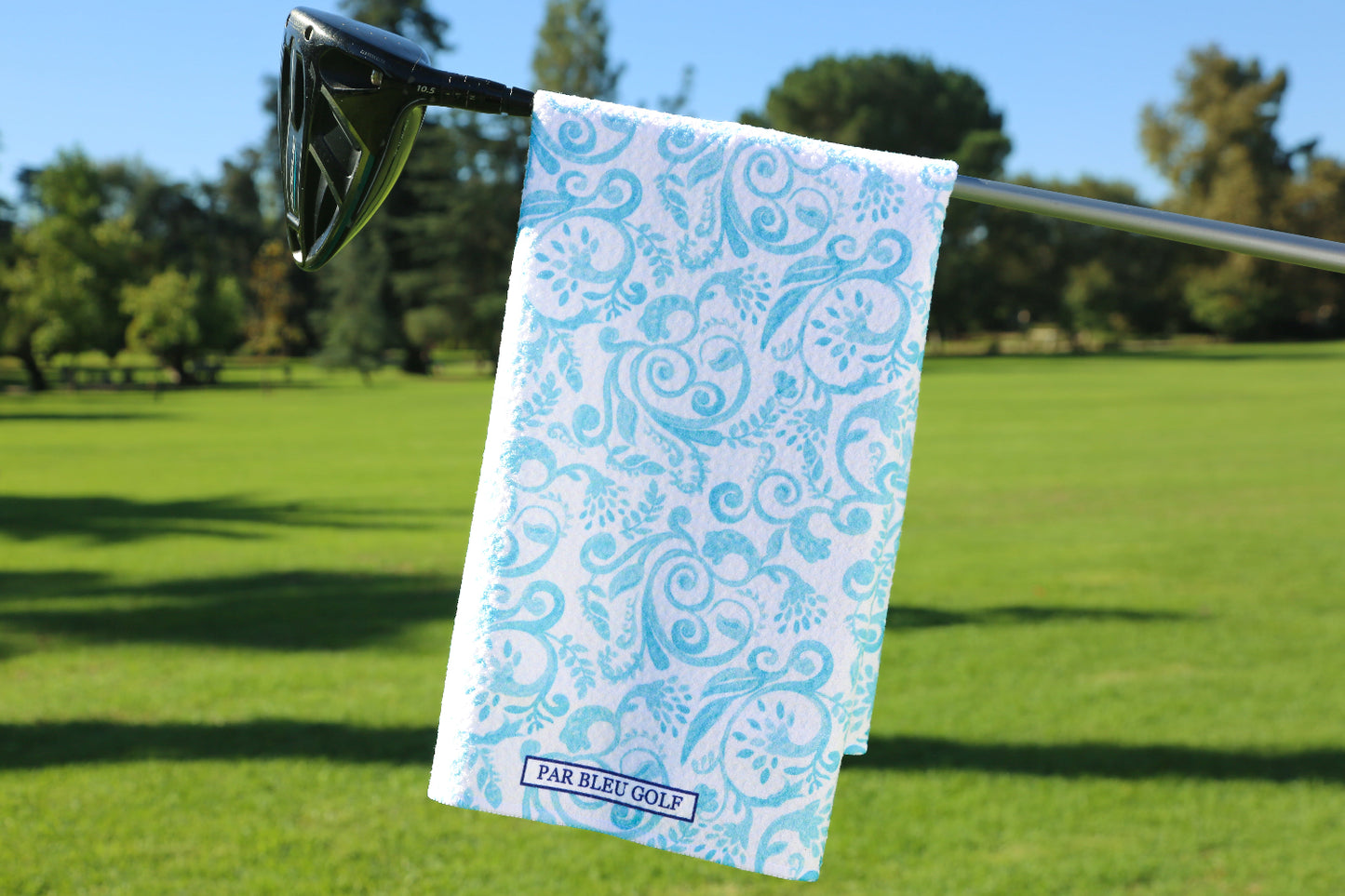 Light teal and white Toile golf towel hanging on a club outdoors, elegant microfiber towel for women golfers