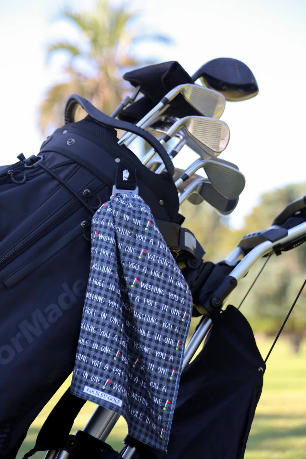 Black “Hole in One” golf towel clipped to golf bag, premium microfiber with modern design