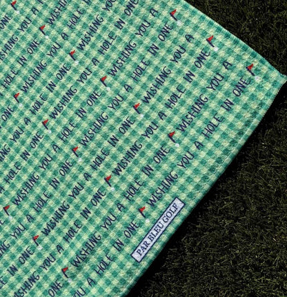 Close-up of microfiber golf towel with repeating “Wishing You a Hole in One” message and Par Bleu Golf tag