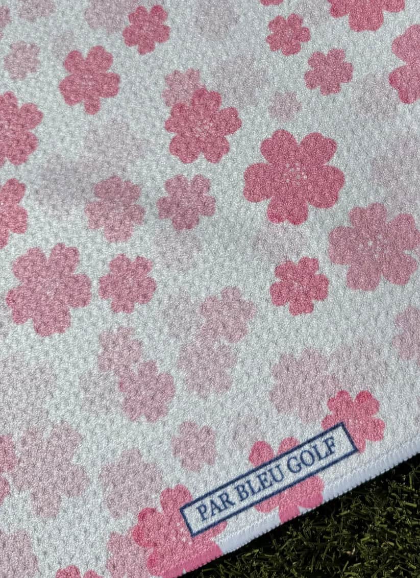 Close-up of Par Bleu’s Pretty in Pink Floral microfiber towel with delicate cherry blossom pattern and logo tag