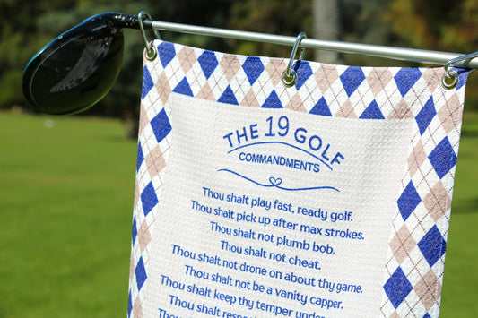 Golf towel with The 19 Golf Commandments text hanging on club with blue diamond border design