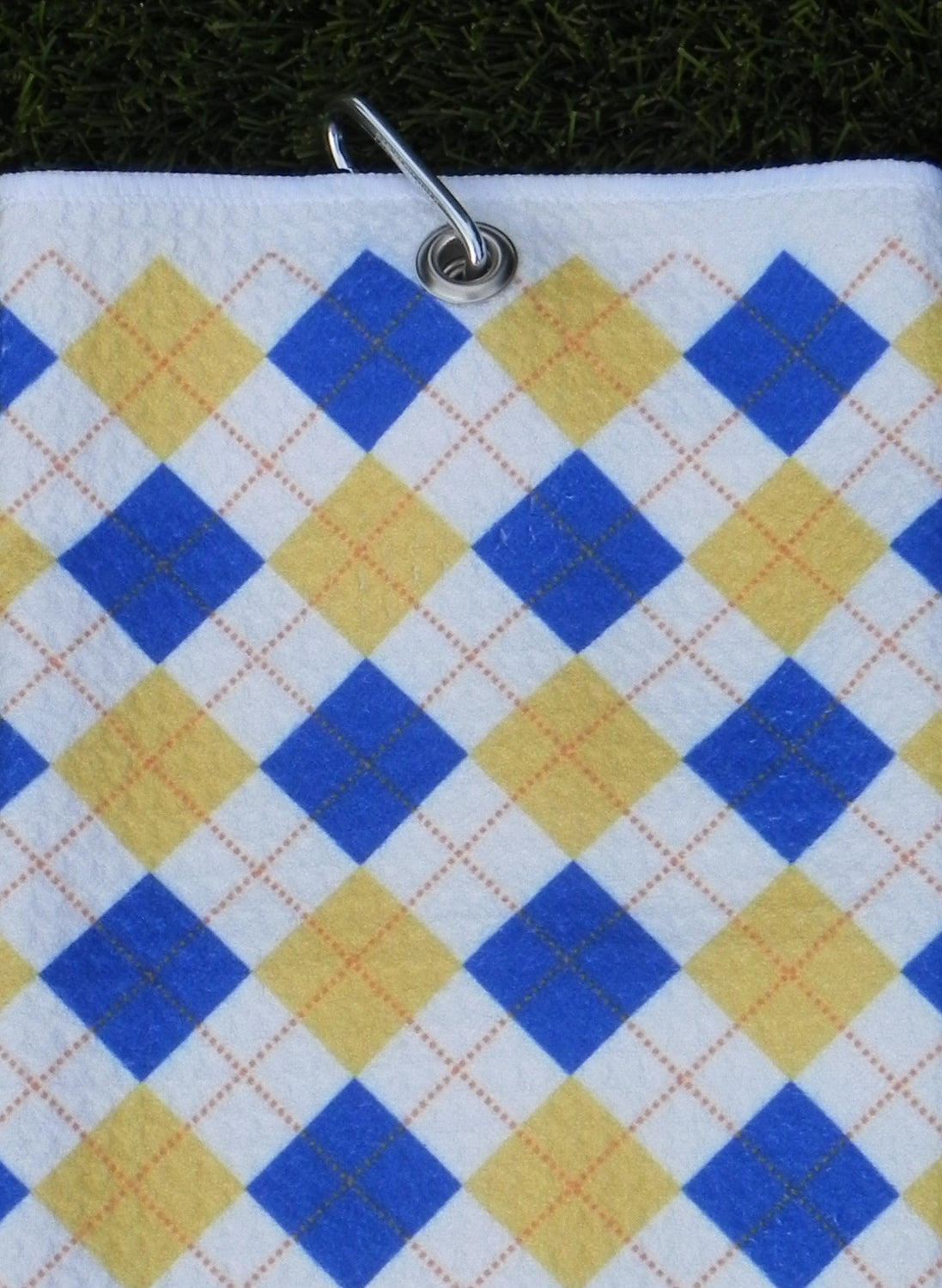 Blue and yellow golf towel with classic argyle design hanging from durable carabiner clip