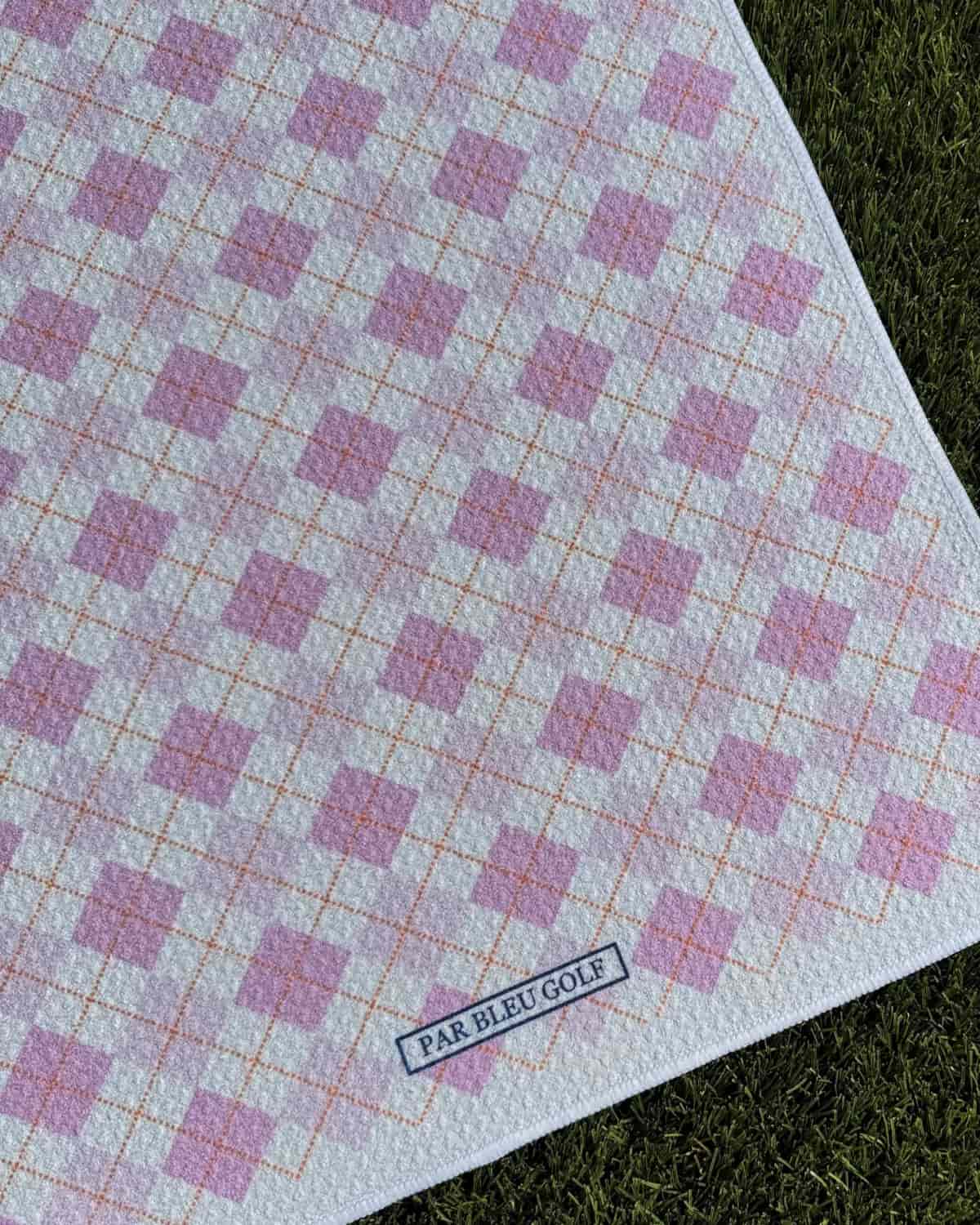 Close-up of The Argyle Chipper: Pink microfiber golf towel with Par Bleu logo and diamond pattern