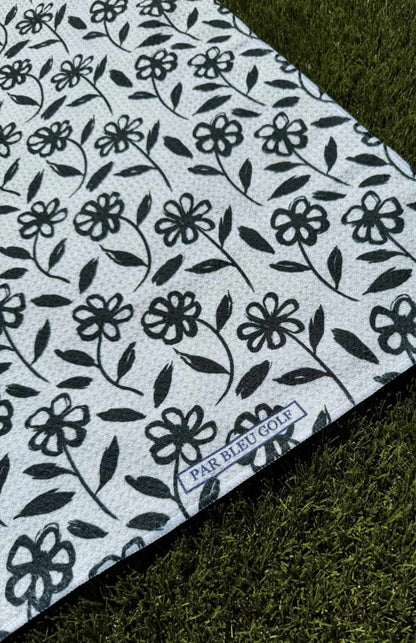 Close-up of The Black Daisy microfiber golf towel featuring black daisy pattern and Par Bleu logo
