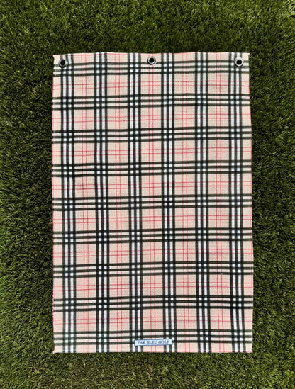 Burr Plaid golf towel laid flat on green grass showing full plaid pattern