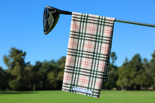 Burr Plaid golf towel hanging on a club with trees and blue sky on the golf course