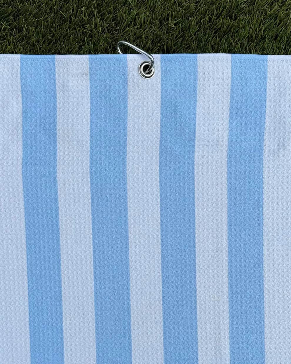 Cabana Stripe golf towel hanging vertically with carabiner and light blue and white stripes
