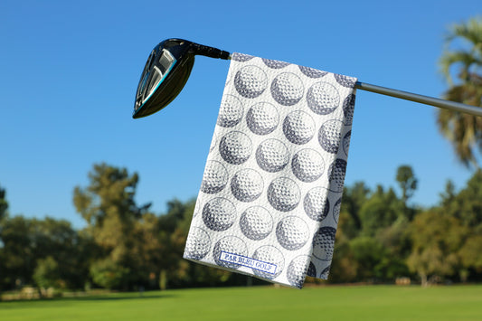 The Golf Ball: Grey microfiber golf towel hanging on a club on the golf course with blue sky