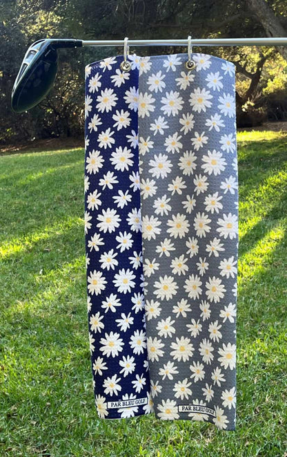 Grey and Blue Daisy golf towels hanging side by side outdoors, premium floral golf accessories