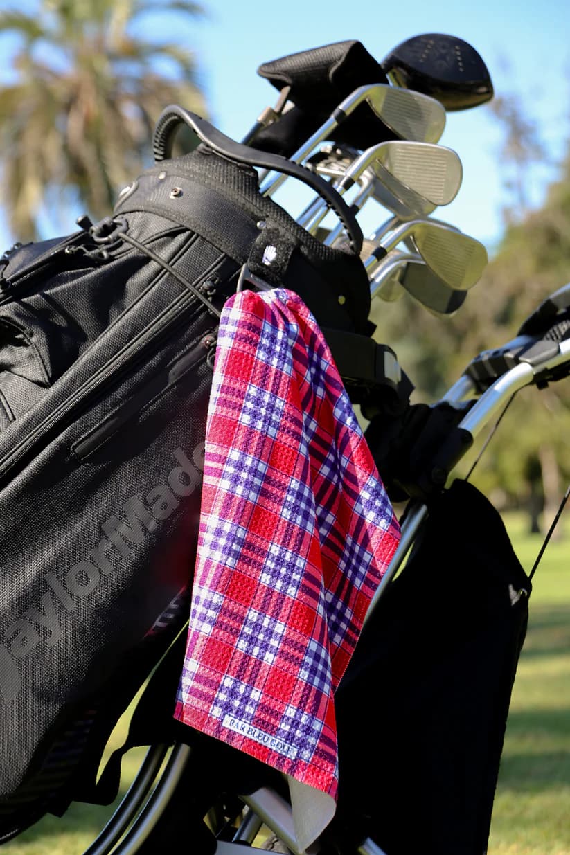 Bold red plaid golf towel clipped to black golf bag on course, stylish and practical golf gift